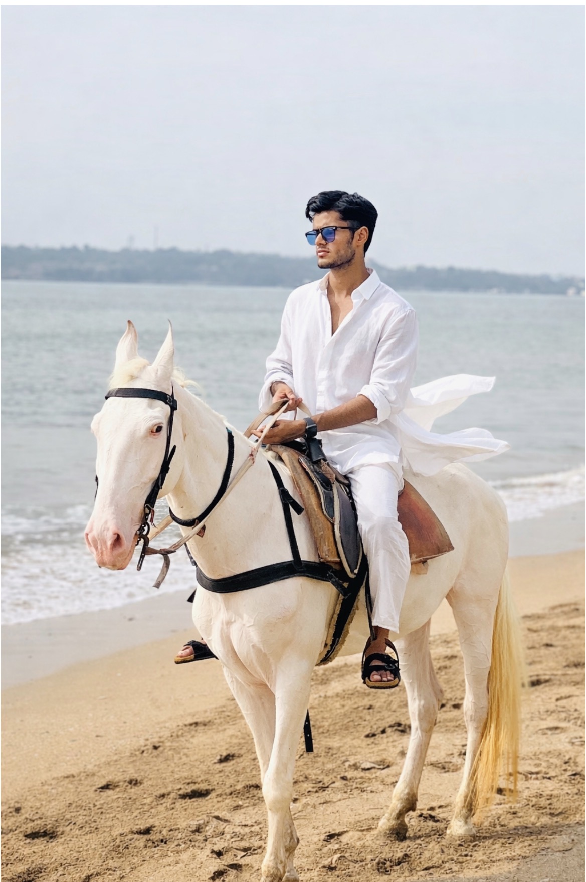 Atharva Sharma on white horse at the beach in white linen